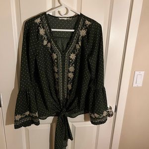 Women’s olive green fall top with tan floral embroidery.